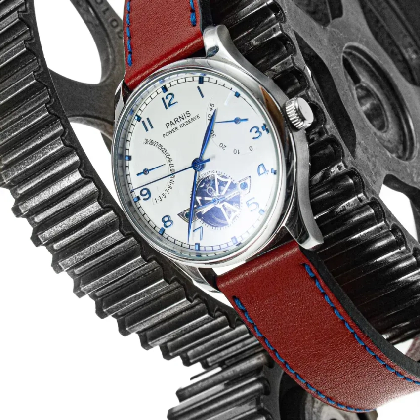 Zegarek Parnis z jasną tarczą i niebieskimi indeksami, w towarzystwie czerwonego paska z niebieskimi przeszyciami